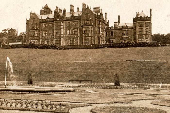 A historical, sepia tone image shoes Worsley Hall, a large Elizabethan manor house, overlooking manicured gardens.